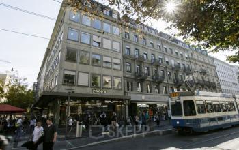 Well-lit office space rental at Bahnhofstrasse 100, Zürich Center with modern furnishings and a bustling city view.